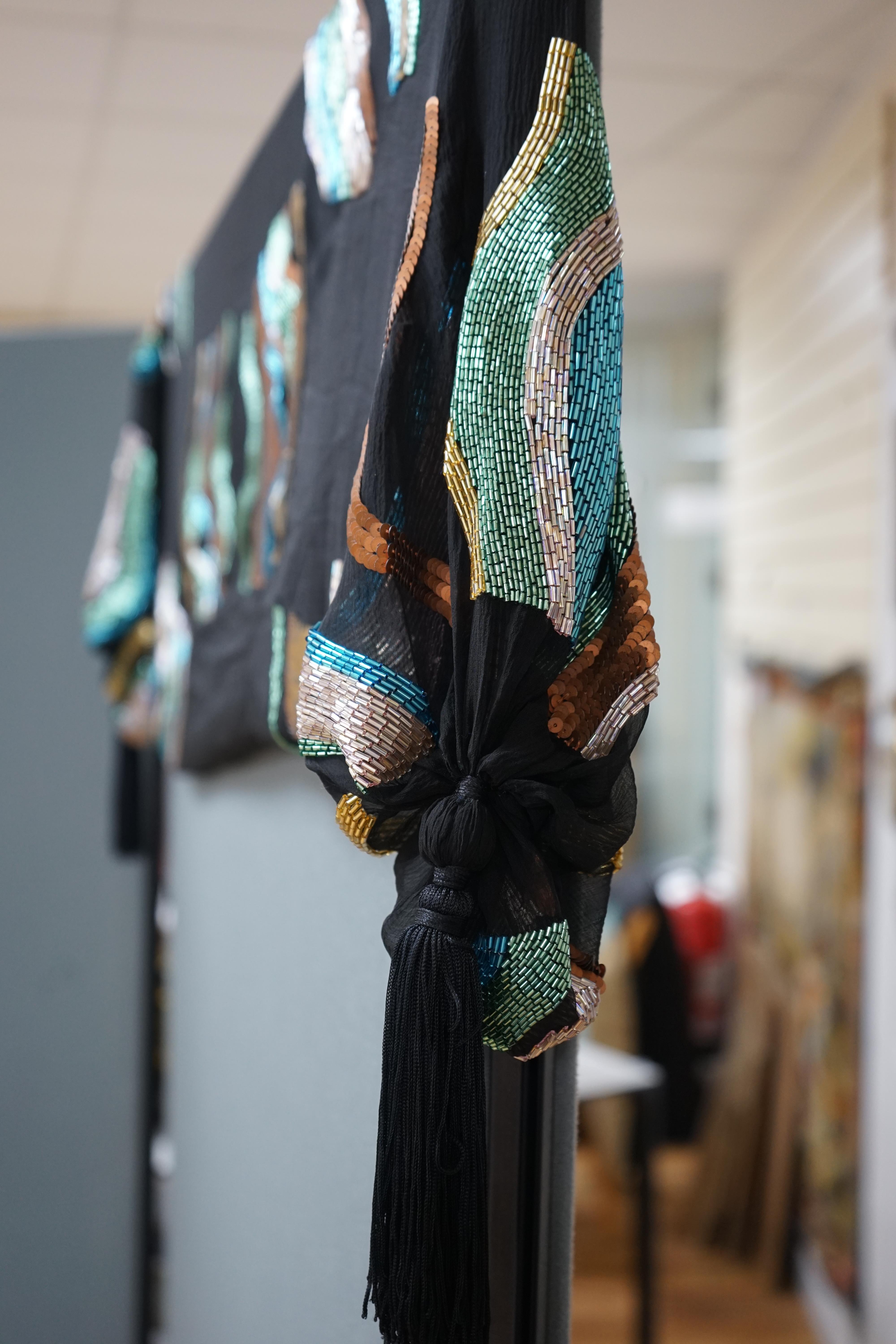 An Artemista Sartoria Italian chiffon bead worked and tasselled evening stole. Worked in bronze, gold, silver, green and turquoise sequins and beads on black chiffon and tasselled each end, 158cm long not including tasse